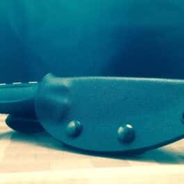 The Kydex sheath for the Benchmade Steep Country is laying on a wooden table.
