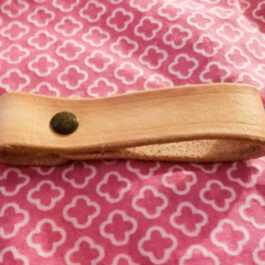 A Leather Dangler Loop sitting on top of a pink and white cloth.