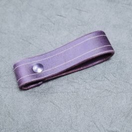 A Leather Dangler Loop laying on a gray surface.