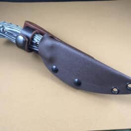 a Benchmade Saddle Mountain Skinner Kydex Sheath that is sitting on a table.