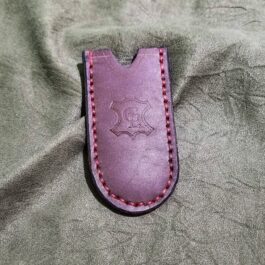 A purple Leather Pocket Slip for the Benchmade Proper sitting on top of a bed.