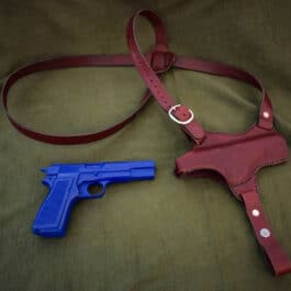 brown Handmade Leather Shoulder Holster laid on a cloth next to a blue gun- renaissance clothing - renaissance clothing men - renaissance clothing women - renaissance clothing near me - renaissance art clothing - renaissance era clothing - renaissance costume ideas