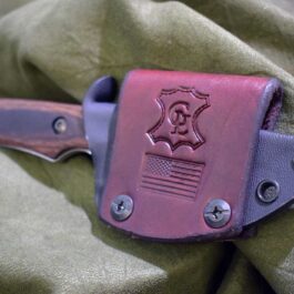 a pink and purple Scout Style Kydex Sheath for Benchmade Hidden Canyon Hunter on a green cloth.