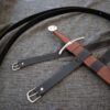a knife with a leather strap on a bed.