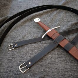 a knife with a leather strap on a bed.
