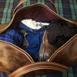 A Bison Leather Duffel Bag with clothes inside of it.