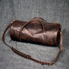 A Bison Leather Duffel Bag sitting on top of a bed.