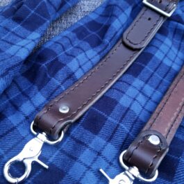 a close up of Upgraded Leather Suspenders on a plaid cloth.