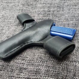 a black Handmade Leather Snap Loop Pancake Holster Style 2 laying on a gray carpet.