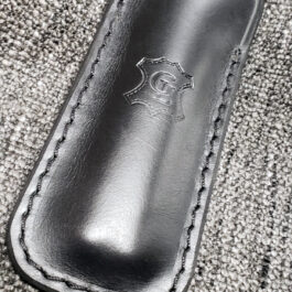 A black Leather Balisong Slip sitting on top of a gray carpet.