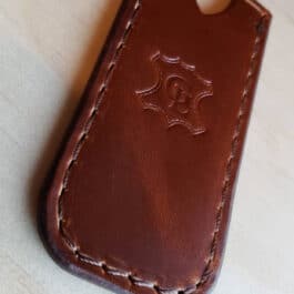 A Leather Pocket Slip for the Benchmade Proper sitting on top of a wooden table.