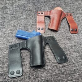 Three Handmade Leather Snap Loop Pancake Holster Style 2s in different colors, placed on a gray surface.
