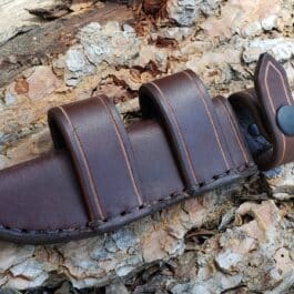 A brown Leather Scout Sheath for the Short Ka Bar Fighting Knife on a tree trunk.