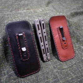 three different types of Benchmade 85/87 Balisong Slips with Pocket Clips sitting on a couch.