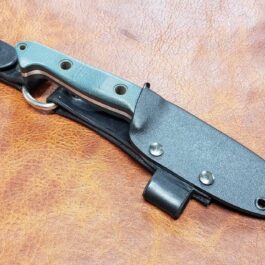 The Benchmade Bushcrafter Kydex Sheath is sitting on a leather surface.