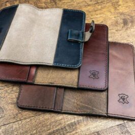 Three Field Notes Wallets sitting on top of a wooden floor.