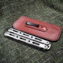A Benchmade 85/87 Balisong Slip with Pocket Clip sitting on top of a green cloth.