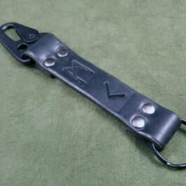 A black leather handmade leather keychain with two holes on it.