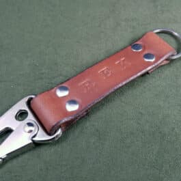 A Handmade Leather Keychain with holes on it.