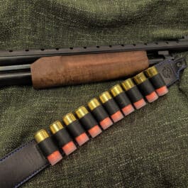 A black Handmade Leather Rifle Sling with horizontal ammo loops and ammunition laid on a cloth - Grommet's Leathercraft - renaissance clothing - renaissance art clothing - renaissance era clothing - leathercraft supplies - leathercraft accessories - leathercraft store near me - quality leather craft