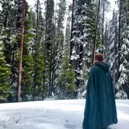 a man wearing a blue Linen Hooded Cloak on the snow - renaissance clothing - renaissance clothing men - renaissance clothing women - renaissance clothing near me - renaissance art clothing - renaissance era clothing - renaissance costume ideas