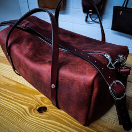 A Bison Leather Duffel Bag sitting on top of a wooden table.