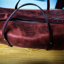 A Bison Leather Duffel Bag sitting on top of a wooden table.