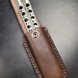 A molded leather belt pouch for a Benchmade Balisong with two knives in it.