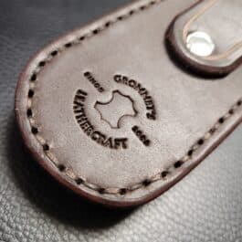 A close up of a Molded Leather Belt Pouch for a Benchmade Balisong on a table.