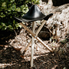 a black leather camp stool with wooden legs