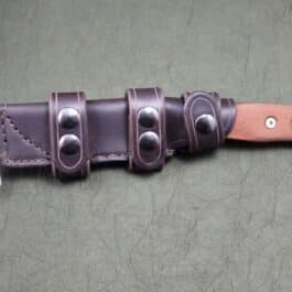 A handmade leather scout sheath for the TOPS Fieldcraft Knife with four holes in it.