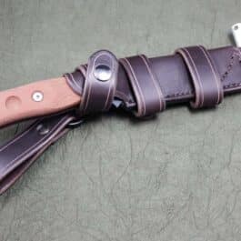 A Handmade Leather Scout Sheath for the TOPS Fieldcraft Knife with a leather handle on a table.