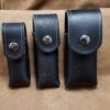 Three handmade black leather pouches with metal buttons.