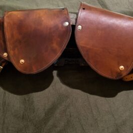 a pair of leather saddles sitting on top of a bed.