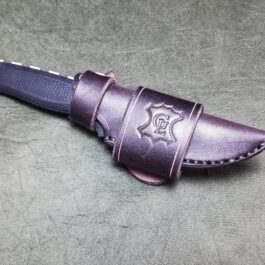 a knife with a leather sheath on a gray surface.