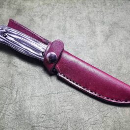 a knife with a leather sheath on a table.