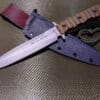 A Kydex Sheath for the TOPS Wild Pig Hunter that is laying on a table.