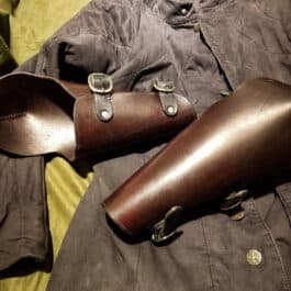 a pair of brown leather shoes laying on top of a bed.