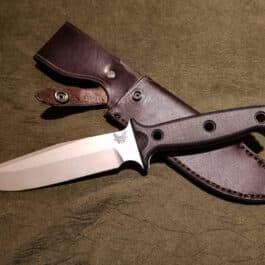 a knife with a leather sheath on a table.