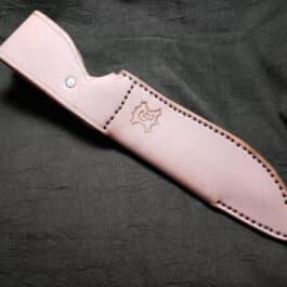 a pink leather knife case sitting on top of a black cloth.