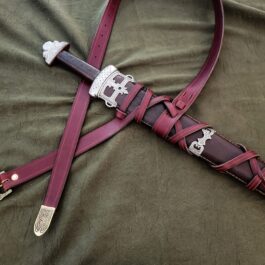An Integrated Sword Belt laying on top of a bed.