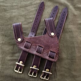 a pair of brown leather suspenders on a green sheet.