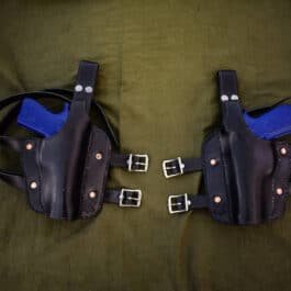A couple of Handmade Leather Thigh Holsters sitting on top of a bed.