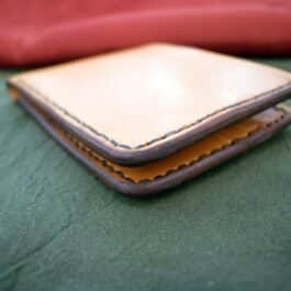 A pair of Custom Handmade Bifold Leather Wallets sitting on top of a bed.