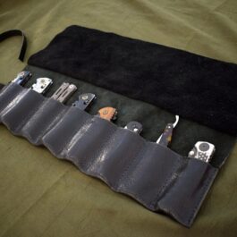 a handmade leather knife/tool roll with a cell phone inside of it.