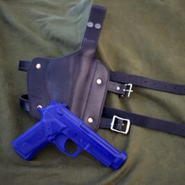 A blue gun and a Handmade Leather Thigh Holster on a bed.