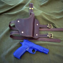 a Handmade Leather Thigh Holster and a gun on a bed.