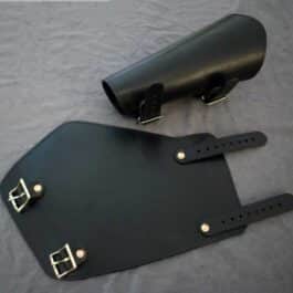 a pair of Greenwood Vambraces sitting on top of a bed.