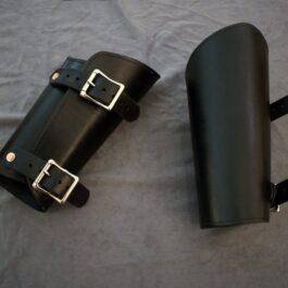 a pair of Greenwood Vambraces sitting on top of a bed.