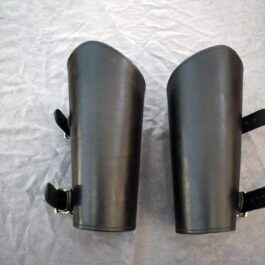 a pair of black Greenwood Vambraces on top of a white sheet.